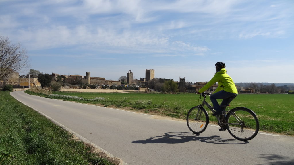 noia en bicicleta que va per un camí asfaltat cap a Peratallada