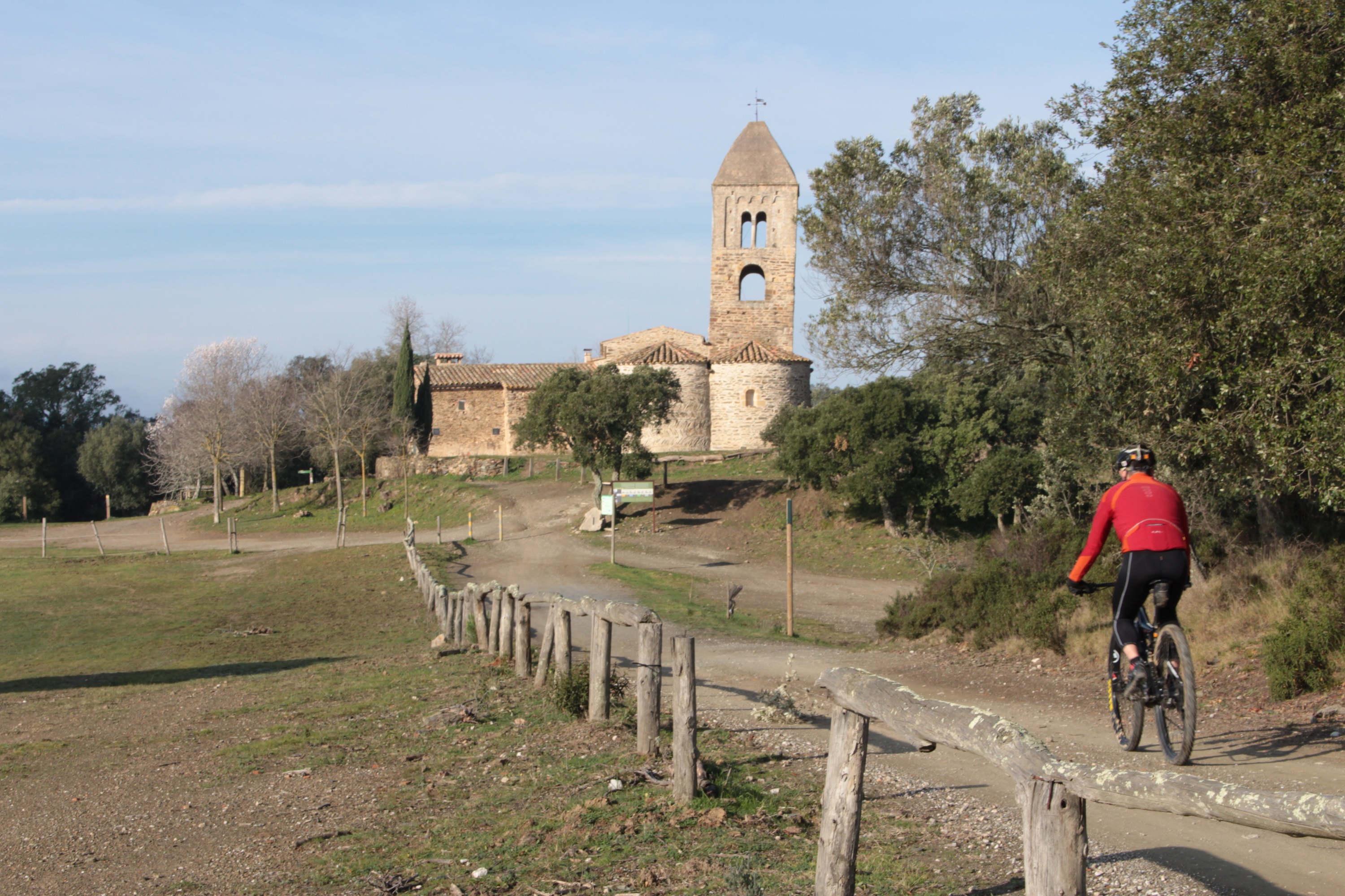 Església de fitor al fons i un noi amb bicicleta btt que hi va arribant