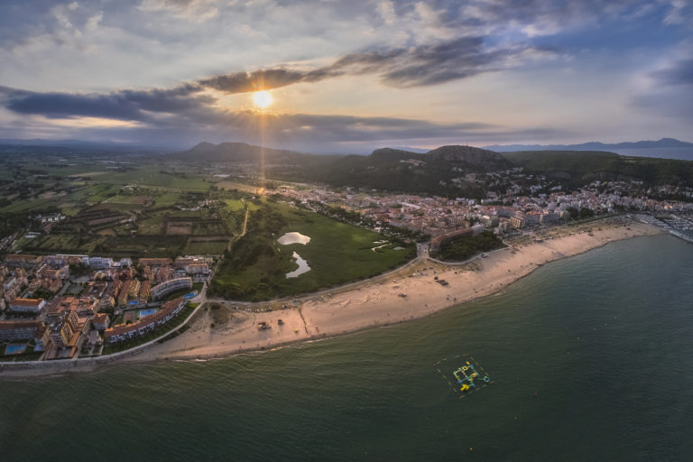 platja de sant antoni, mar a l'esquerra i platja amb persones prenent el sol i amb parasols a la sorra