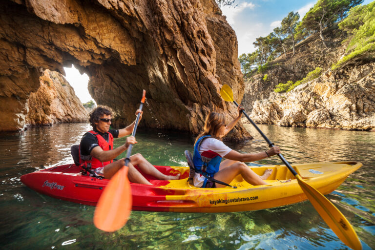 A primer pla kayak pel riu ter amb un noi i una noia, semblen joves. i a darrera un altre kayak amb una parella, semblen els pares