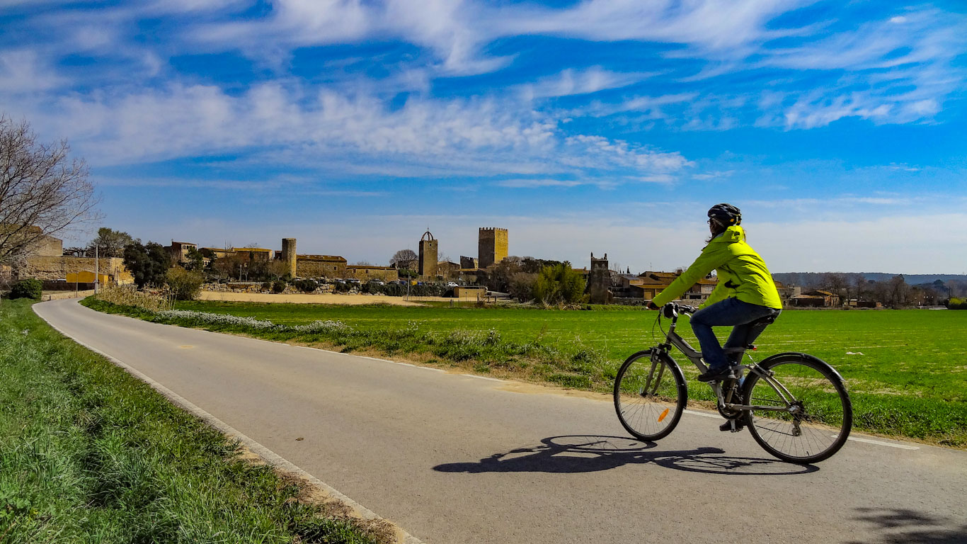 noia en bicicleta que va per un camí asfaltat cap a Peratallada