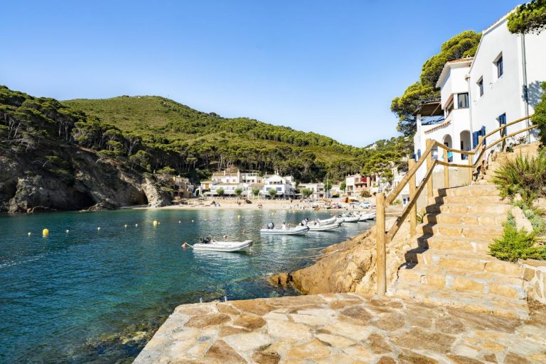 platja de sant antoni, mar a l'esquerra i platja amb persones prenent el sol i amb parasols a la sorra