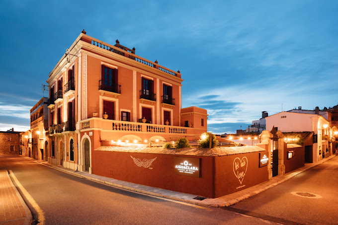 Hotel Es Portal. Masia a primer pla i fotografia de nit. al costat una terrassa nova amb vidres i que es veuen les taules a dins.